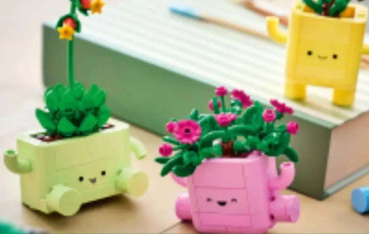 Drei fröhliche Pflanzen aus LEGO-Steinen in bunten Töpfen mit Gesichtern. Sie sehen aus, als würden sie sich über das Wachstum freuen.