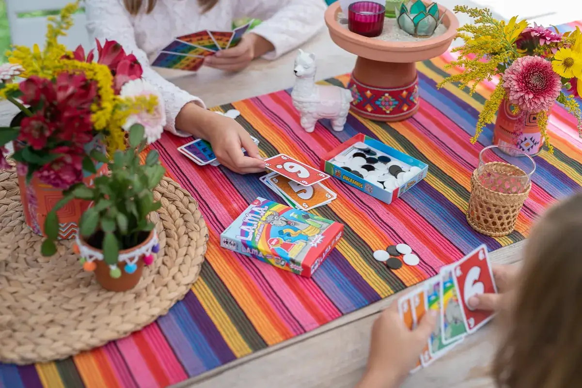 Bunte Tischdecke, Blumen und Spiele f&uuml;r einen kindergeburtstag kreativ. Kinder spielen Karten und Brettspiele.