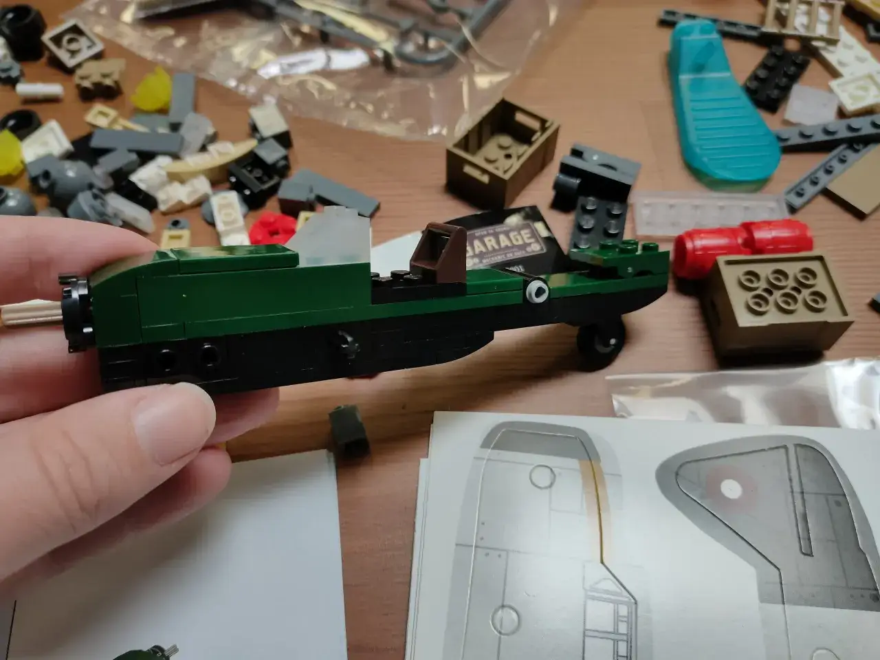 Bunte Bausteine liegen verstreut, während eine Hand ein grünes Modellauto hält. Die cada bauanleitungen liegen daneben.
