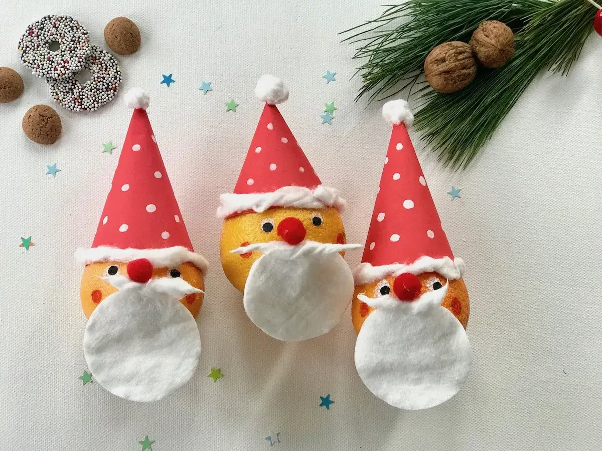 Drei lustige Nikolaus-Gesichter aus Orangen, perfekt f&uuml;r Nikolaus basteln U3. Mit roten M&uuml;tzen und wei&szlig;en B&auml;rten.