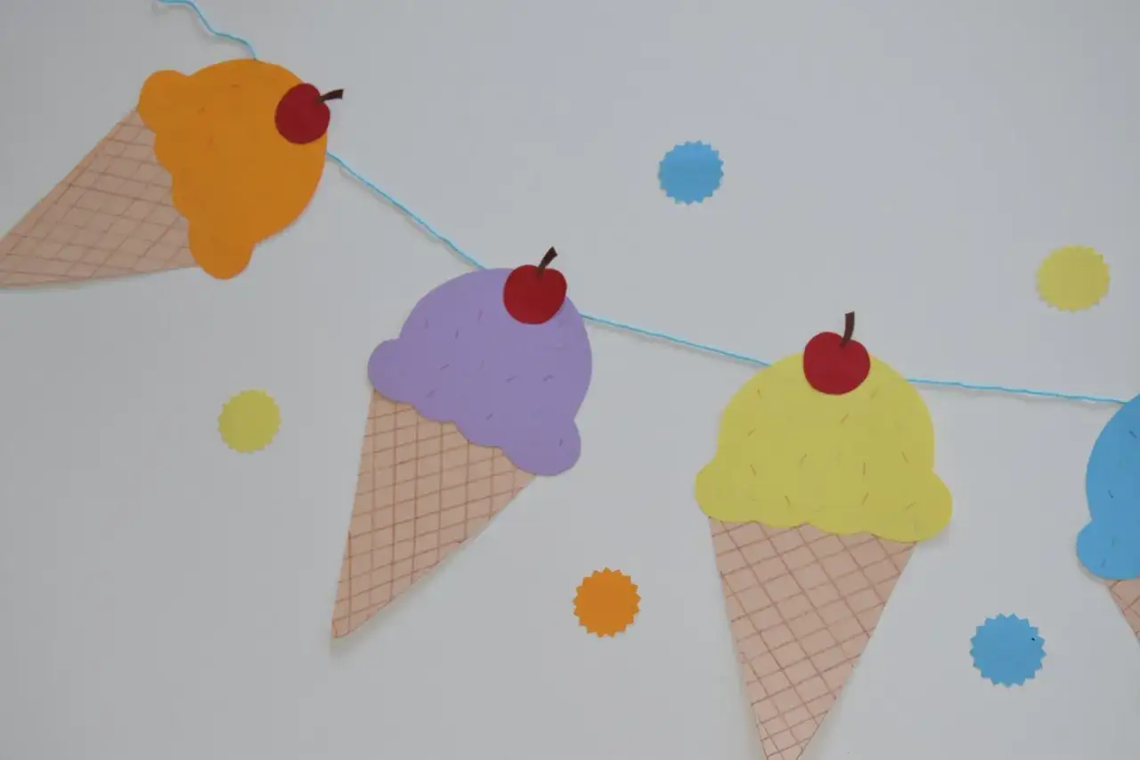 Bunte Papier-Eiscreme-Girlande, perfekt als eis basteln vorlage für Kinder. Mehrere Eistüten in verschiedenen Farben mit Kirschen.