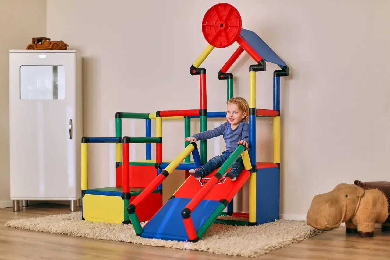 Kleines Kind rutscht auf bunter Spielburg. Tolle quadro aufbau ideen für Kinderzimmer.