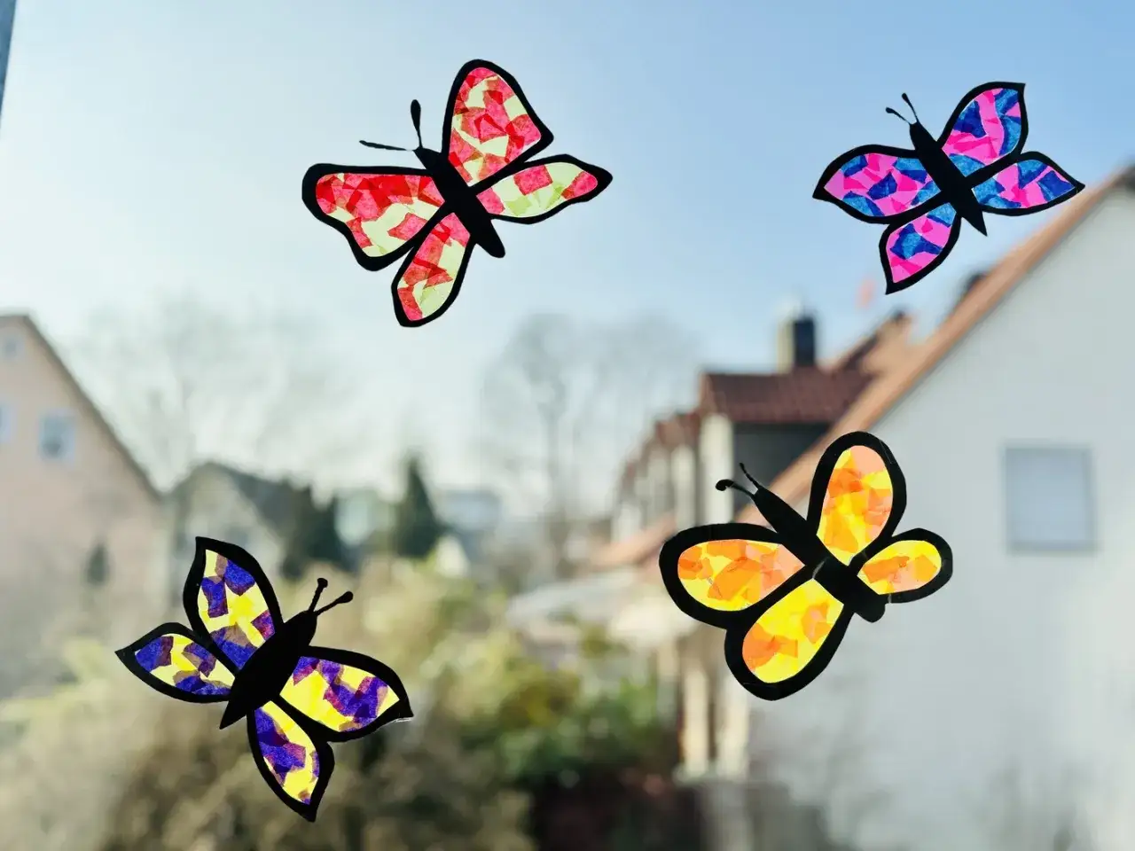 Bunte Schmetterlinge aus Seidenpapier, ein tolles Projekt für Fensterfolie basteln Kinder. Sie schmücken das Fenster mit leuchtenden Farben.