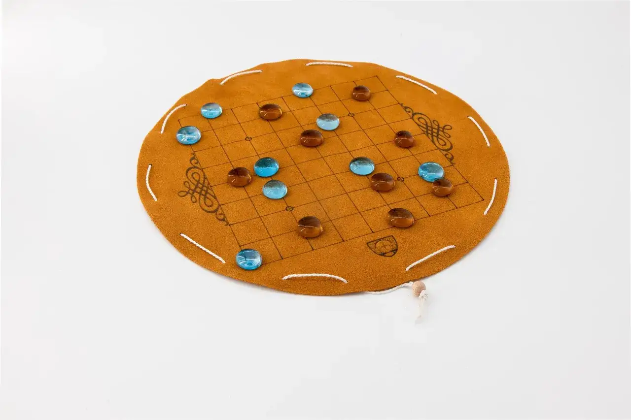 Rundes, braunes Brettspiel aus Leder mit einem Gittermuster und blauen und braunen Glassteinen. Ein Beispiel für japanische Brettspiele.