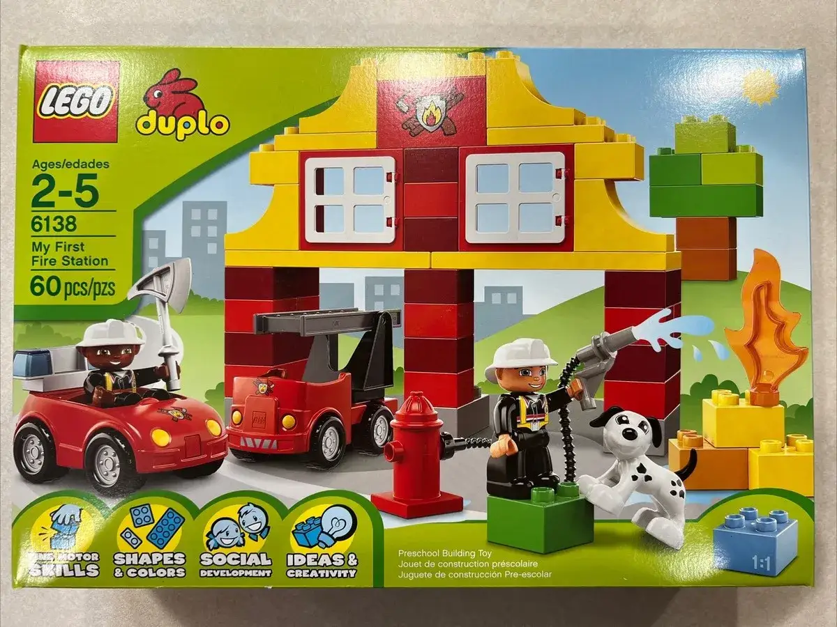 LEGO DUPLO Feuerwehr Anleitung: Ein Feuerwehrmann löscht mit einem Schlauch einen brennenden Baum. Ein Hund schaut zu.